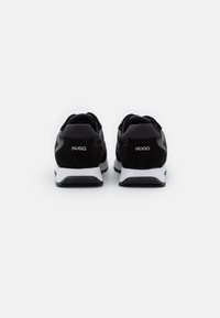 Sneaker in suede nero e mesh con suola intermedia bianca; marchio "HUGO" sul tallone; design atletico classico, forma arrotondata, superficie testurizzata.