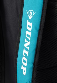 Dunlop sports bag features a black body with a bright turquoise strap, textured surface, and bold white logo, designed for durability and functionality.