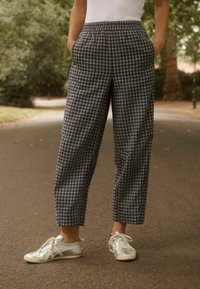 Blauwe en witte broek met ruitpatroon, elastische tailleband, rechte pijpen en zijzakken, gecombineerd met zilveren sneakers.