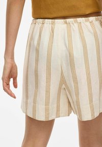 Pantalones cortos a rayas de tejido ligero; base crema con rayas verticales marrón amarillentas, cinturilla elástica, pliegues planchados en la parte delantera.