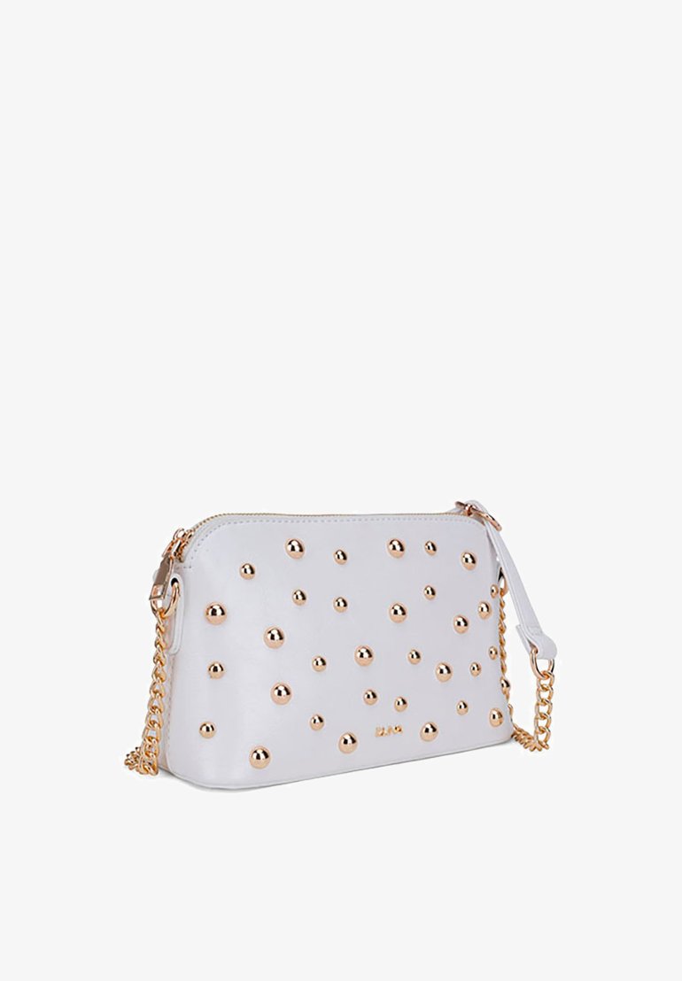 Bolso de mano de cuero blanco con cierre de cremallera, adornado con remaches en tono dorado, correa de cadena y una textura suave con acentos redondeados.