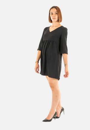 Abito nero con scollatura a V e maniche a tre quarti, caratterizzato da una silhouette fluida a A. Abbinato a tacchi alti neri.