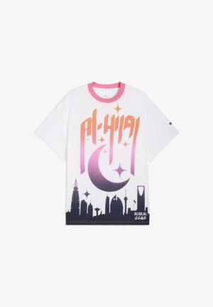 Camiseta blanca de manga corta con el texto "AL-HILAL" en un colorido degradado y un diseño de luna creciente con la silueta de una ciudad en la parte inferior.