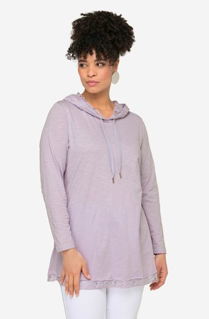 Hellblau-lange Ärmel Hoodie, mit einem Spitzenbesatz am Saum, Kordelzug am Halsausschnitt und weicher, strukturierter Stoffqualität. Über weißen Hosen getragen.