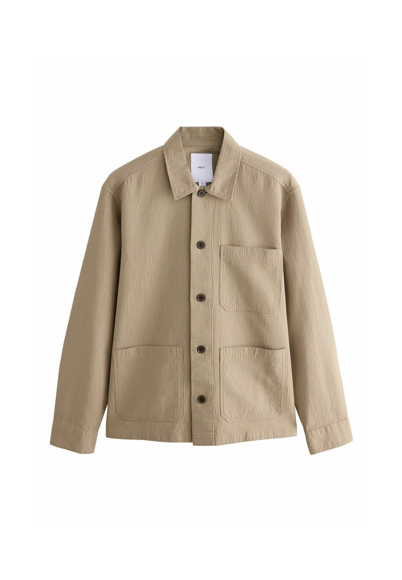 Beige Jacke mit strukturierter Oberfläche, Knopfleiste und klassischem Kragen. Sie verfügt über zwei große Fronttaschen und eine einzelne Brusttasche.