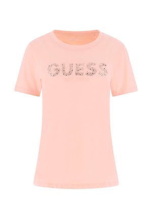 Šviesiai rožinė trumpomis rankovėmis marškinėliai su užrašu „GUESS“ dekoruotais rašmenimis ir „EST. 1981“ spausdinta po prekės ženklo pavadinimu.