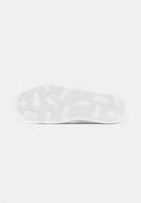 Semelle de basket blanche avec des motifs de semelle en zigzag et rectangulaires sur un fond blanc uni.