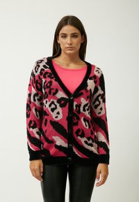Roze en zwarte panterprint cardigan met een V-hals, knoopsluiting aan de voorkant en lange mouwen. Gemaakt van een zachte, donzige stof.