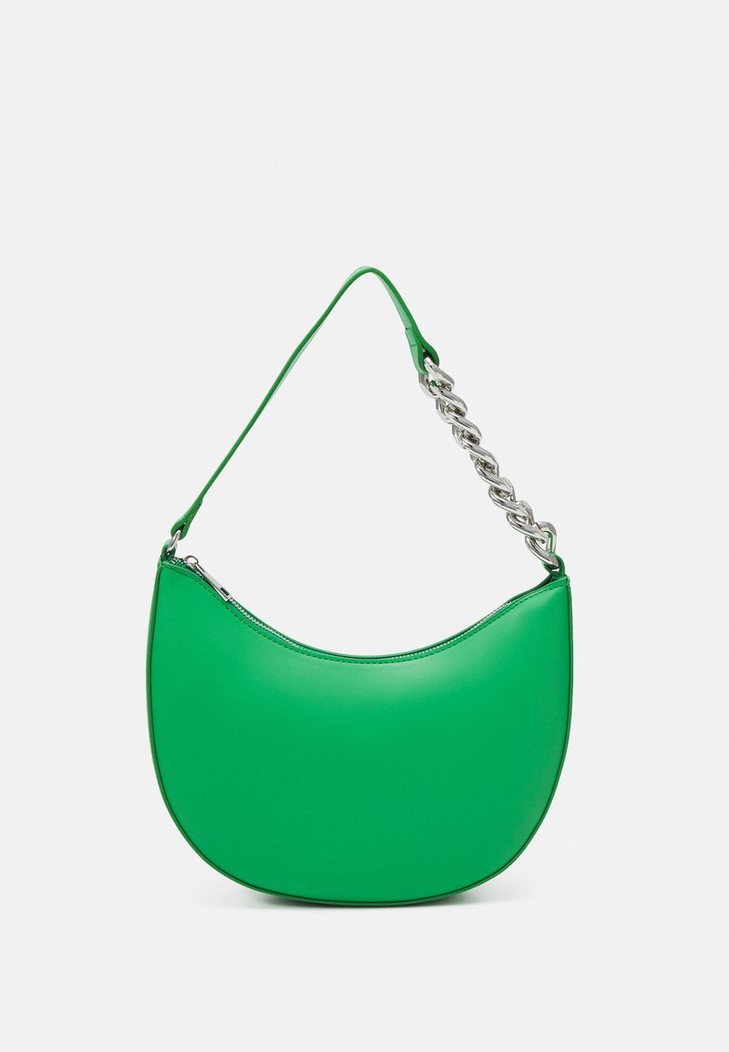 Sac à main vert en forme de croissant avec une chaîne argentée et une bandoulière en cuir, fermeture éclair au sommet sur fond gris.