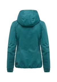 Turkooise capuchonjas met lange mouwen, elastische manchetten en een kleine zwarte patch nabij de onderzoom, gezien van achteren.