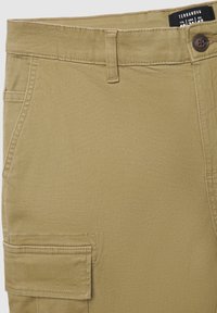 Pantaloni cargo color khaki realizzati in tessuto misto cotone, con chiusura a bottone, zip e una tasca laterale con dettagli a patta.