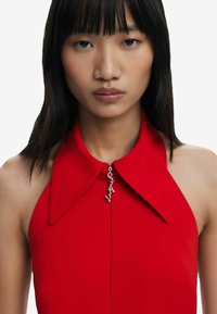 Red halter dress featuring a large collar and a zipper accent. Smooth texture with shiny silver hardware detail at the neckline.