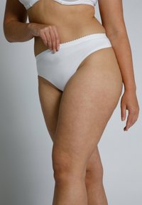 Mutande bianche in cotone a vita alta con una fascia elastica ondulata, texture liscia e copertura moderata sulla coscia.