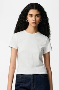 Biała bawełniana koszulka z krótkimi rękawami i okrągłym dekoltem. Miękka w dotyku i dopasowany fason, zestawiona z ciemnymi jeansami z denimu.