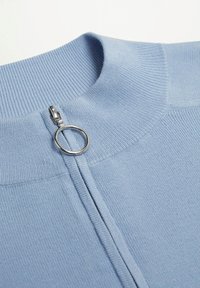 Suéter azul claro con diseño de cuello alto, con cierre plateado y tirador circular, y textura acanalada en el cuello y el cuerpo.