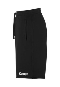 Zwarte sportshorts van zacht materiaal, met een trekkoord in de taille, zijzakken en een wit 'Kempa' logo aan de onderkant links.