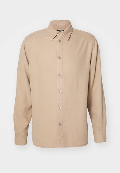 Beige hosszúujjú ing, gombos gallérral. Puha anyagból készült, elöl gombolható pánttal és egyszerű varrási részletekkel rendelkezik.