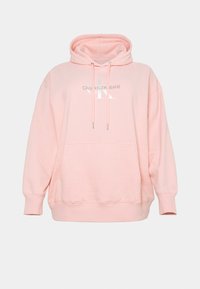 Sudadera oversized rosa hecha de tejido suave, con capucha ajustable, bolsillo delantero y un logo blanco impreso en el pecho.
