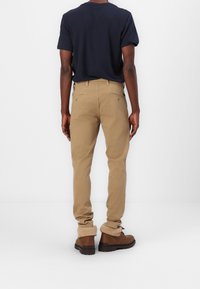 Beige byxor med slim fit och två bakfickor, kombinerat med en marinblå t-shirt och bruna ankelstövlar med fuskpälsfoder.