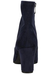 Mörkblå mocka ankelskåp med en kraftig klack, subtila stygnsdetaljer och en dragkedja i ryggen för stängning.