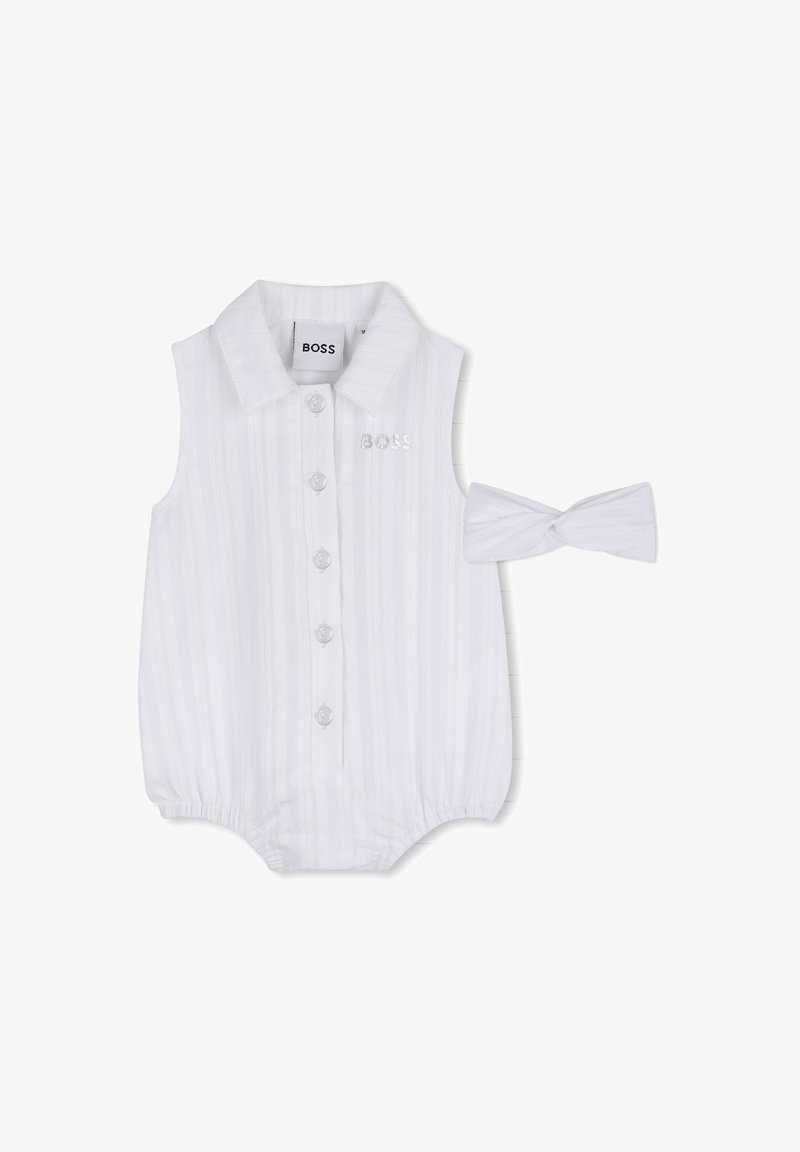 Combinaison blanche sans manches à rayures verticales, fermeture à boutons et col à revers. Comprend un bandeau blanc assorti avec un nœud.