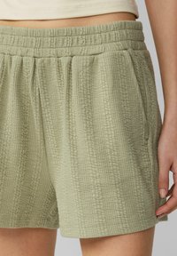 Lichtgroene shorts van een textuurstof met een gerimpelde elastische tailleband en zijzakken, met een comfortabele, losse pasvorm.