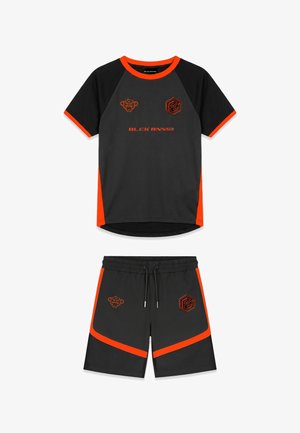Zwart-oranje sportshirt met korte mouwen en bijpassende korte broek met logo's en tekst "BLCK BNNS" op de voorkant.