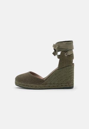 Espadryle na koturnie w oliwkowym kolorze z zakrytym noskiem, plecionym jutowym obcasem i wiązaniami wokół kostki.