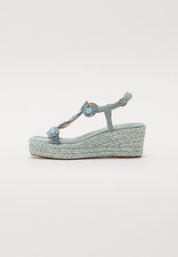 Sandale compensée bleu clair avec semelle en jute tressé, ornée de pierres décoratives sur la bride et d'une boucle ajustable à la cheville.