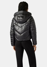 Giubbotto imbottito corto, metallico e nero, con motivo a chevron e cappuccio. Presenta una texture trapuntata e polsini elastici.