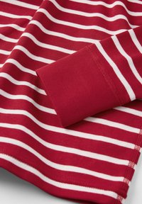 Punainen ja valkoinen raidallinen pitkähihaisessapaidassa on ribbireunukset, ja siinä on sileä puuvillakangas sekä suora helma.