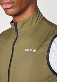 Olivovo zelená cyklistická bunda s vysokým golierom, zipsovým zapínaním a priedušnou sieťovinou. Logo 'GripGrab' na prednej strane.