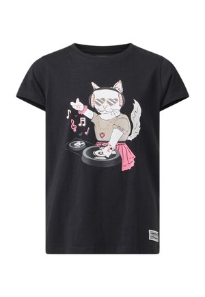 Fille portant un sweat à capuche et un pantalon roses avec des baskets marron, un t-shirt noir avec un motif de chat DJ, debout devant un fond uni.