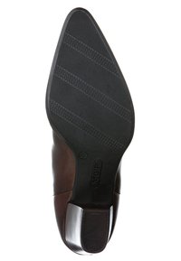 Chaussure en cuir brun avec un bout pointu et une semelle en caoutchouc noir texturé. Présente un design élégant et un accent argenté sur le talon.