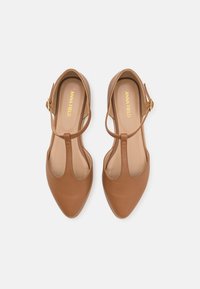 Bruine leren T-band schoenen met spitse neuzen, voorzien van een gladde afwerking en een kleine gouden gesp op de enkelband.