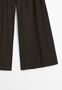 Pantalons large à rayures noires avec une texture lisse, présentant des rayures verticales dans différentes nuances, et un design épuré et ajusté.