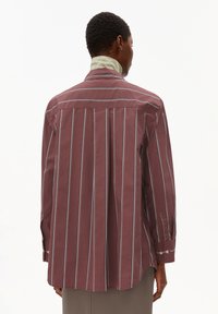 Maroon striped shirt with long sleeves, button cuffs, and a curved hem. Features vertical stripes in lighter colors and a soft texture.