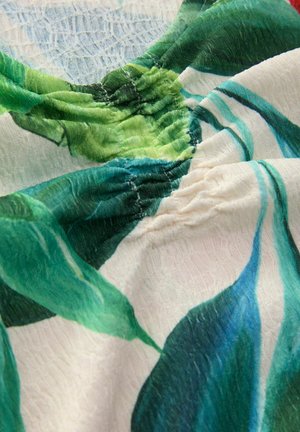 Materiał w kwiatowy wzór z zielonymi liśćmi na białym tle. Tekstura jest lekko pomarszczona z marszczonymi szwami przy dekolcie.