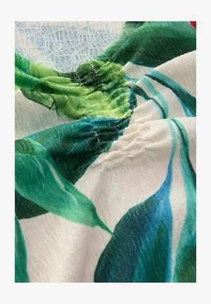 Floral-patterned fabric featuring green leaves on a white background. The texture is slightly crinkled with gathered seams at the neckline.