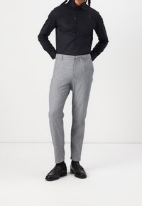 Svart skjorta med knappar och lång ärm, kombinerad med ljusgrå skräddarsydda byxor och svarta loafers, med en mjuk textur och klassisk passform.