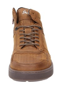 Chaussure montante en cuir marron avec un bout perforé, semelle en caoutchouc marron foncé et lacets contrastants en tan. Présente un logo sur la languette.