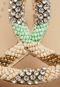 Sandalias de cuentas con cuentas verdes, crema y doradas, adornadas con strass transparentes. Superficie texturizada con detallados patrones intrincados.
