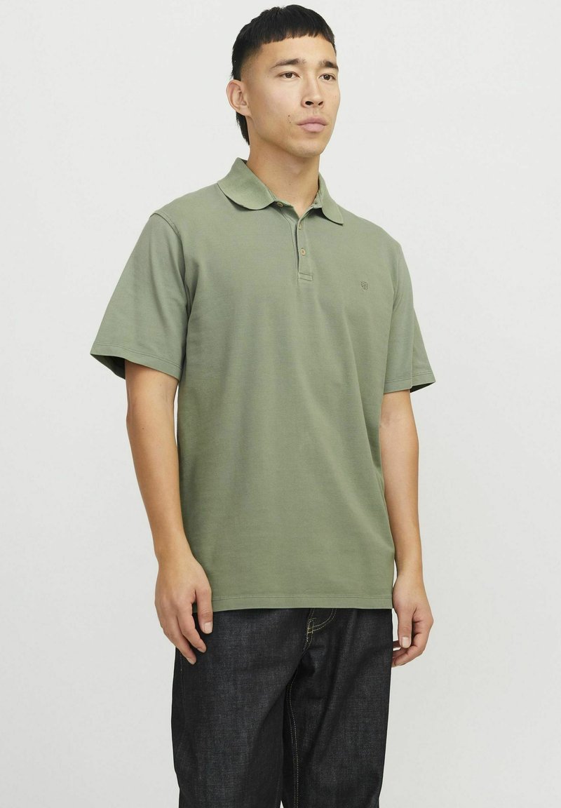 Polo shirt verde oliva con colletto classico, maniche corte e un logo discreto sul petto, realizzato in materiale di cotone testurizzato.