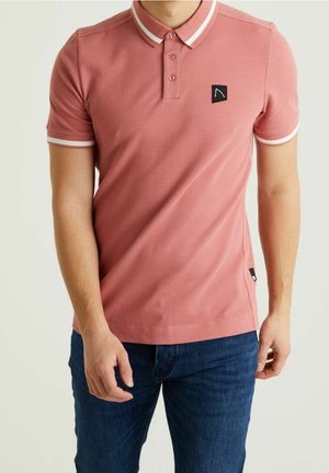 Camisa polo rosa con un tejido texturizado, cuello blanco en contraste y acentos en las mangas, además de un pequeño parche negro con el logo en el pecho.