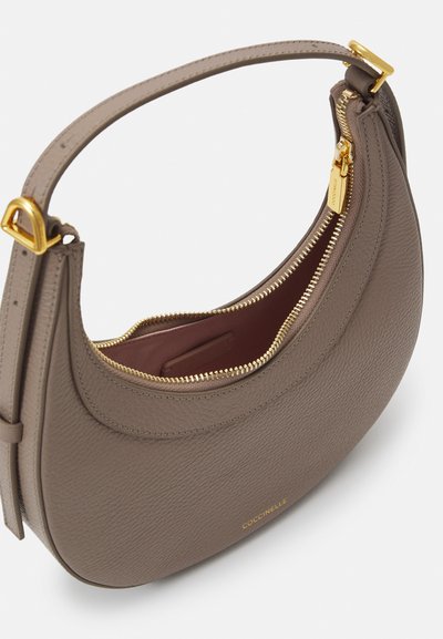 Sac à main en cuir texturé gris avec un design courbé, une fermeture éclair dorée et un accent de logo doré. Le dessus ouvert révèle un intérieur rouge.