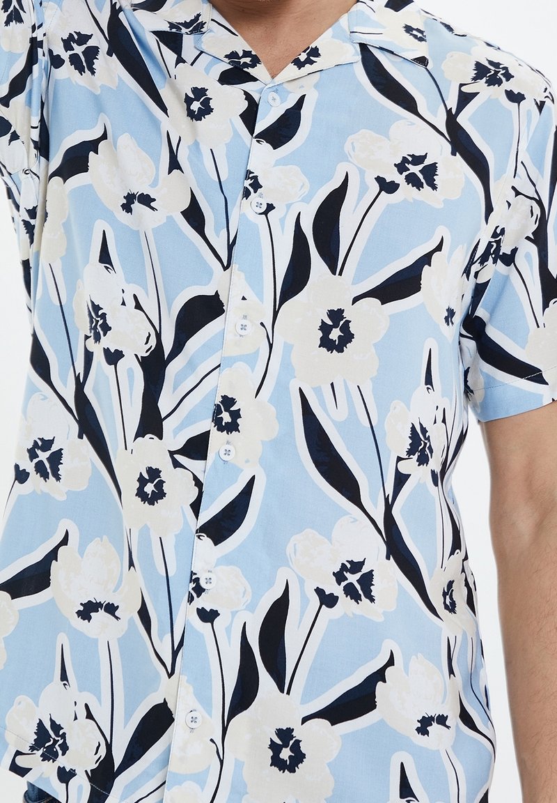 Kurzärmliges Blumenhemd in hellblau, mit großen weißen Blumen und schwarzen Akzenten, einer Knopfleiste vorne und einem klassischen Kragendesign.