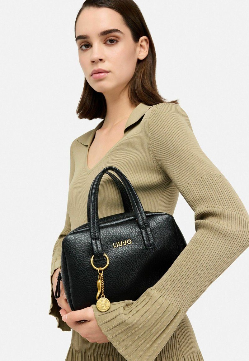 Sac à main en cuir noir texturé avec une forme structurée, des accents en métal doré et un détail de porte-clés. Logo "LIUJO" embossé à l'avant.