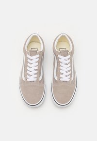 Beige semskinn sneakers med hvite snørebånd, med en hvit sidestripe og svart gummisåle. Klassisk low-top design.