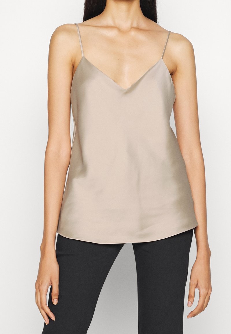 Camisón de satén beige con escote en V, tirantes finos y ajustables, y un dobladillo fluido. La tela tiene una textura suave y brillante.