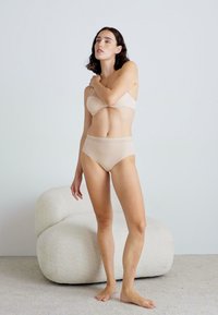 Beige trådløs BH og høy midje brief sett laget av mykt stoff, med delikat blonderkant i livet og sømløse kanter.